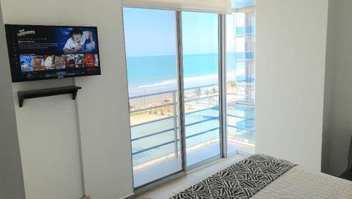 a bedroom with a large window with a view of the beach at ARENA PLAZA DEPARTAMENTO PLAYA con vista al mar in Tonsupa