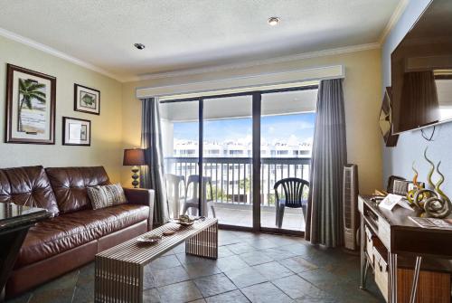 a living room with a leather couch and a balcony at Casa del Mar 379-Neptunes Retreat in Galveston