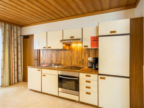 una cucina con armadi bianchi, lavandino e frigorifero di Apartment Vorreiter - UTD150 by Interhome a Uttendorf