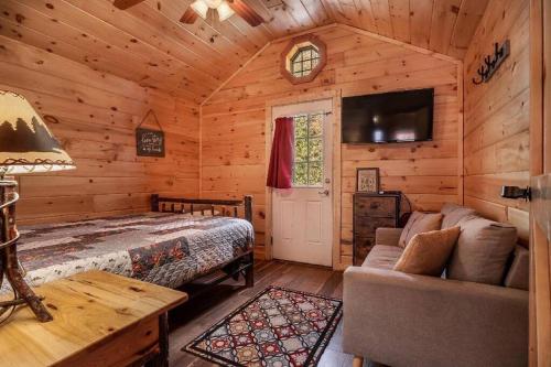 a bedroom with a bed and a couch in a cabin at Sweet Pea Tiny Home in Bryson City