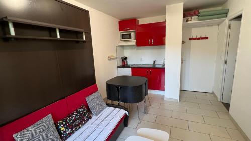 un salon avec un canapé rouge et une cuisine dans l'établissement Appartement 2 pièces rez-de-jardin à 2 pas de la plage et de la thalasso, à Cabourg