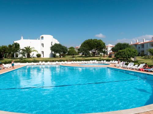 a large blue swimming pool with chairs and a building at Apartment Quinta do Torrejão by Interhome in Porches