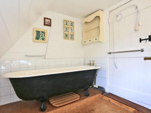 a bath tub in a bathroom with white tiles at Holiday Home Eelsfoot by Interhome in Hemley