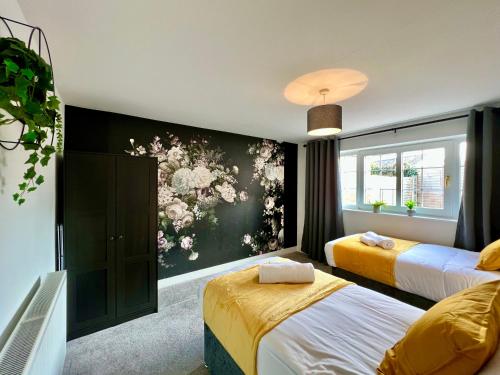 a bedroom with two beds and a wall with flowers at Curzon House Two - Serene Escape Cottage in Cleethorpes