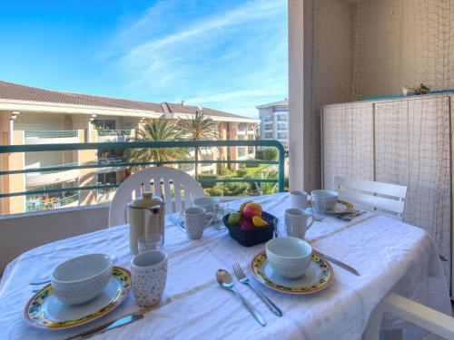 a table with a white table cloth on a balcony at Apartment Le Cesarée-2 by Interhome in Fréjus