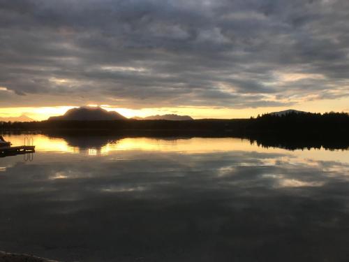 a view of a lake with the sun setting at Holiday Home Seehaus Blue Faak by Interhome in Faak am See