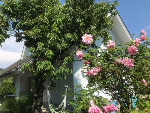 une maison avec des fleurs roses devant elle dans l'établissement Holiday Home Seehaus Blue Faak by Interhome, à Faak am See
