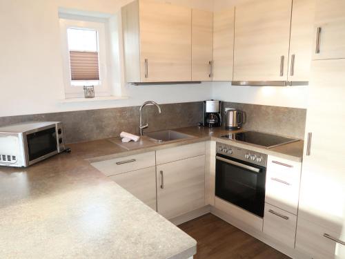 a kitchen with white cabinets and a sink and a microwave at Holiday Home Wattwurm by Interhome in Dagebüll
