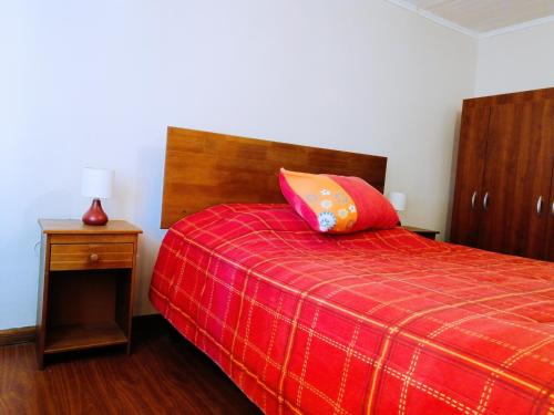 um quarto com uma cama vermelha e um cobertor vermelho em Hostel Casa Descanso Natural em Panimávida