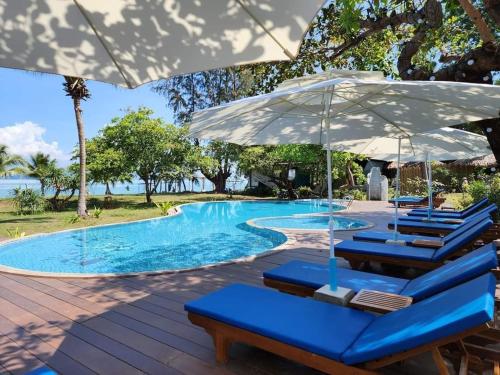 a swimming pool with blue chairs and umbrellas at Better View Koh Yao Yai in Ko Yao Yai