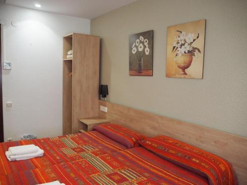 a bedroom with a bed with a red blanket on it at Pensión Acella in Pamplona