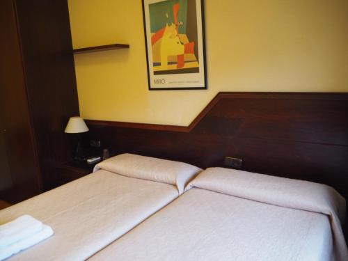 two beds in a hotel room with a picture on the wall at Pensión Acella in Pamplona