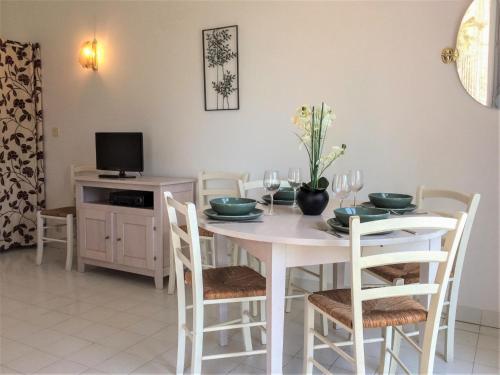 a white dining room table with chairs and a tv at Apartment Les Hauts des Issambres-8 by Interhome in La Garonnette-Plage