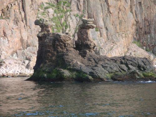 a rock formation in the water next to a mountain at Hotel Sandvig Havn in Sandvig