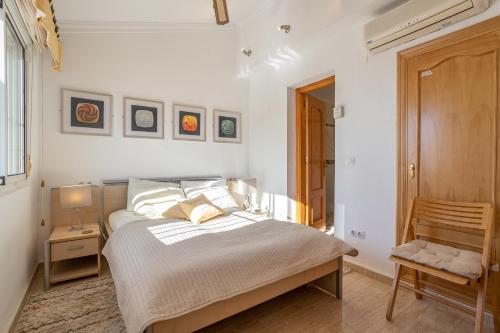 a white bedroom with a bed and a chair at Alto Rey Torrox Beach in Torrox Costa