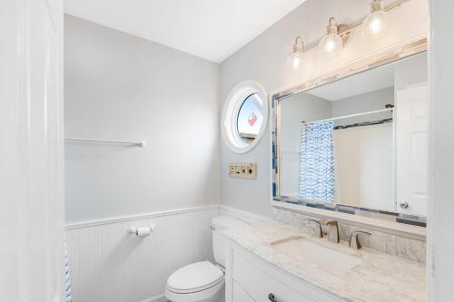 Baño blanco con lavabo y espejo en Close Enough, en Surf City