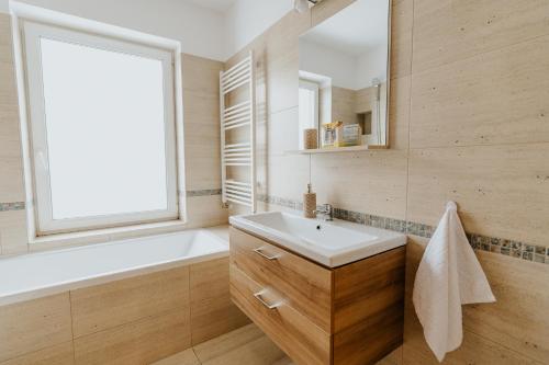 baño con lavabo, bañera y ventana en Lotus Apartman II en Odorheiu Secuiesc
