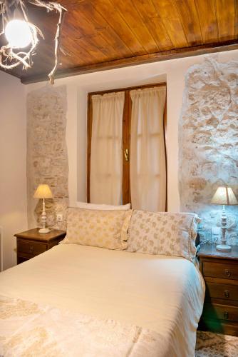 a bedroom with a bed with a stone wall at Lykovrisi Guest House in Arachova