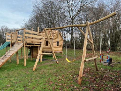 a wooden playground with a slide and swings at Holiday home Gite Saint Donat in Rendeux