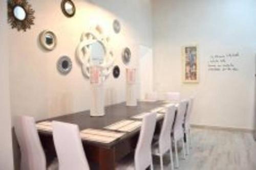 a dining room with a long table and white chairs at APARTAMENTO VEEDOR 19 DÍAS Y MUCHAS NOCHES in Cádiz