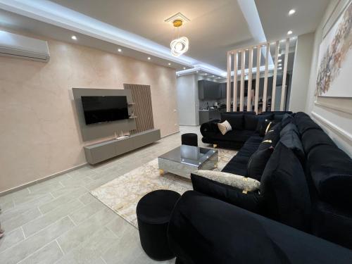 sala de estar con sofá negro y TV en Luxury Apartment in Elbasan, en Elbasan