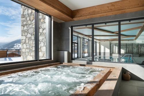 Les Chalets de Joy في لو غراند بورناند: حوض استحمام ساخن في غرفة مع نوافذ كبيرة