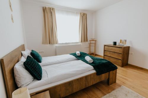 Un dormitorio con una cama con almohadas verdes y una ventana en Lotus Apartman II en Odorheiu Secuiesc