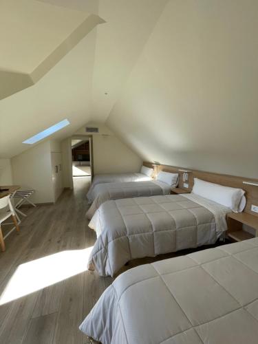 a bedroom with two beds and a table in a attic at APARTAMENTOS TURÍSTICOS GUIANA in Ponferrada