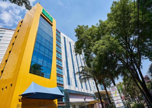 a yellow building with a blue umbrella in front of it at BelAir Business a Wyndham Garden Hotel in Mexico City
