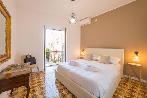 a bedroom with a bed and a desk and a window at Castalia Apartments & Rooms Duomo Taormina in Taormina
