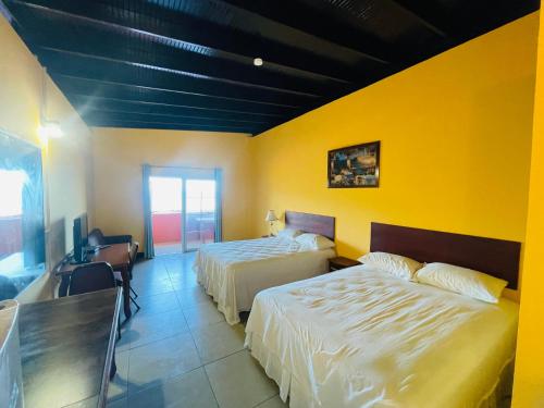 a bedroom with two beds and a yellow wall at Las Cuevas Boutique Hotel in Las Cuevas