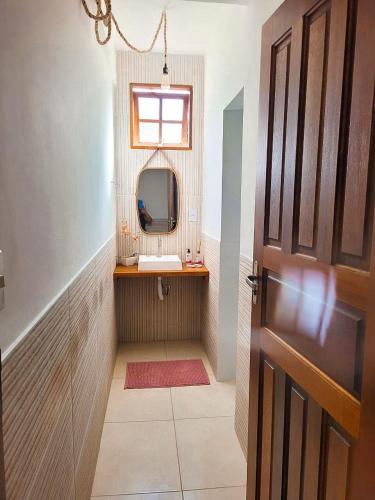 a bathroom with a sink and a mirror and a door at Herdeiros do Pai in Paraty