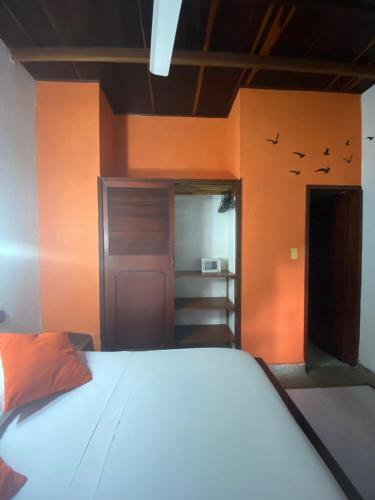Cama en habitación con paredes de color naranja en Hotel Nueva Granada, en Santa Marta