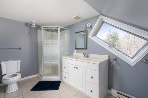 a bathroom with a toilet and a sink and a window at Majestic Retreat in the Laurentians in Morin Heights