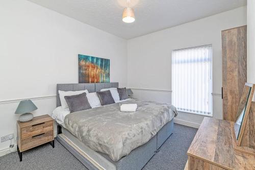 Schlafzimmer mit einem Bett, einem Tisch und einem Fenster in der Unterkunft 2 Bed Holiday House within Walton Area, Liverpool in Liverpool