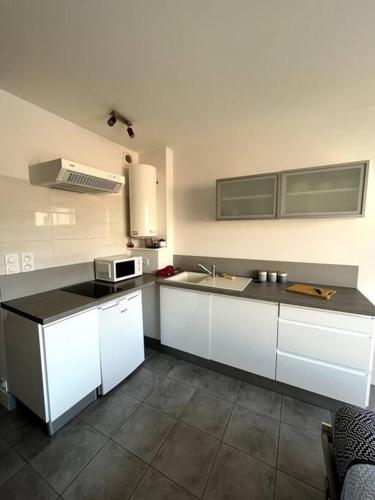 une cuisine avec des armoires blanches et un micro-ondes dans l'établissement Studio équipé moderne à deux pas de la plage, à La Rudelière