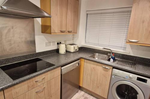 a kitchen with a sink and a washing machine at Greenhithe Cosy Apartment, Netflix and Sport Channels in Kent