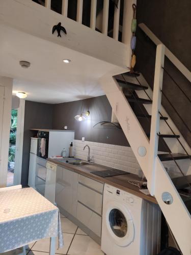 une cuisine avec lave-linge sous un escalier dans l'établissement bord de mer, à Cavalaire-sur-Mer