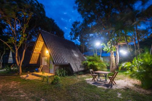 una cabaña en el bosque por la noche con una mesa y sillas en Cashewnut Tree Resort en Ko Lanta