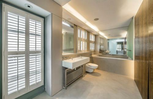 a bathroom with a sink and a toilet and a mirror at Unique,architecturally acclaimed,Notting Hill home in London