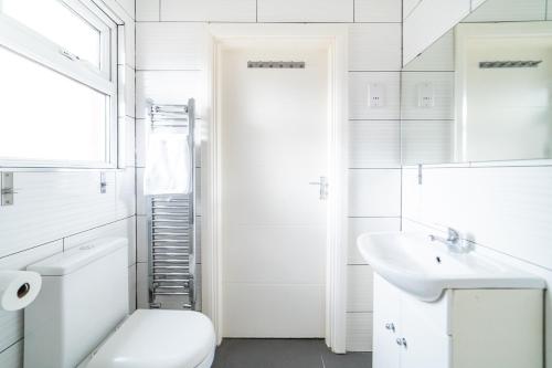 Baño blanco con aseo y lavamanos en (Kensington-Olympia-Museums ) Apartment Central London, en Londres