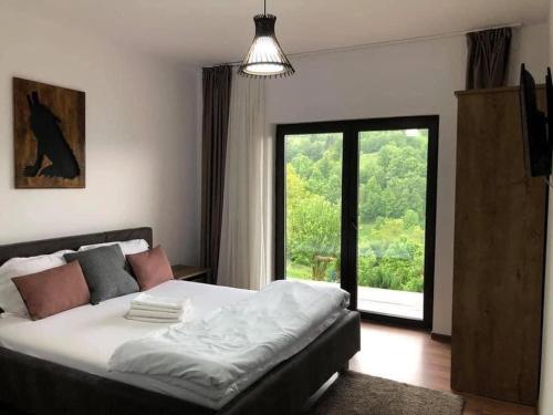 a bedroom with a bed and a large window at Green Yard Doftana in Teşila
