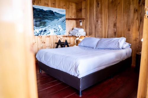 Hotel Casa del Colibri في Güicán: غرفة نوم بسرير في غرفة خشبية