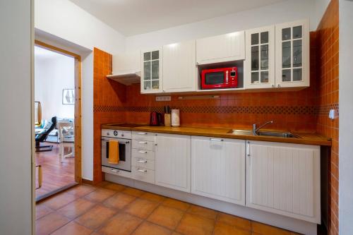 a kitchen with white cabinets and a red microwave at Starý farhof in Kutná Hora