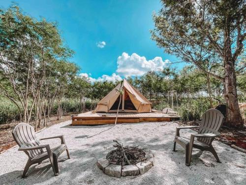 two chairs and a tent in a field at Cute Off Grid Glampsite with WiFi- 5 min from Haleiwa Town in Haleiwa