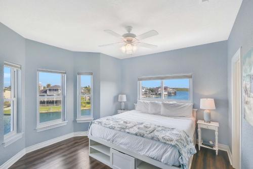 een slaapkamer met een bed, een plafondventilator en ramen bij Livin' the Dream in Galveston
