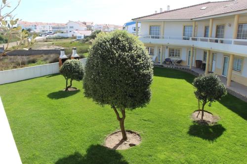a green yard with two trees in front of a house at Baleal, by the sea with swimming pool in Baleal