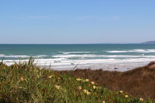 a beach with people walking on the sand and the ocean at Baleal, by the sea with swimming pool in Baleal
