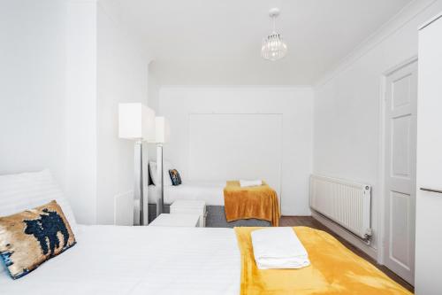 1 dormitorio blanco con 1 cama y 1 silla en 4 bedroom House Free Parking Contractor's Haven, en Chelmsford