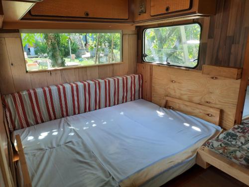 a bed in the back of a rv with two windows at Azienda del Lupo - Caravan mit Ambiente in Bagnone